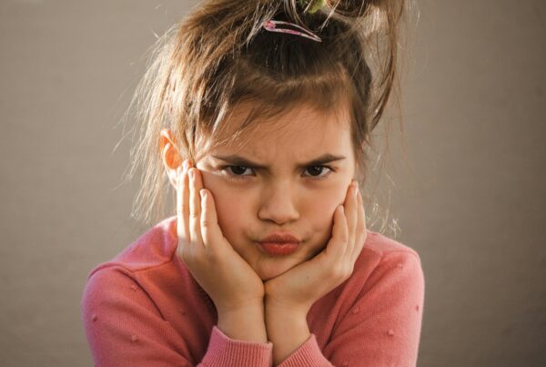 young girl holding face in hands looking angry having meltdown