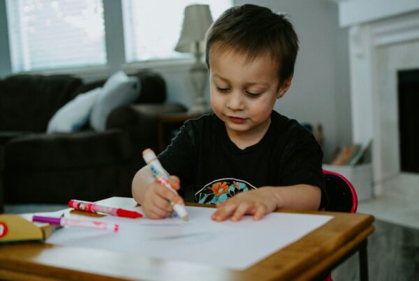 boy drawing with markers on a table in healthy environment