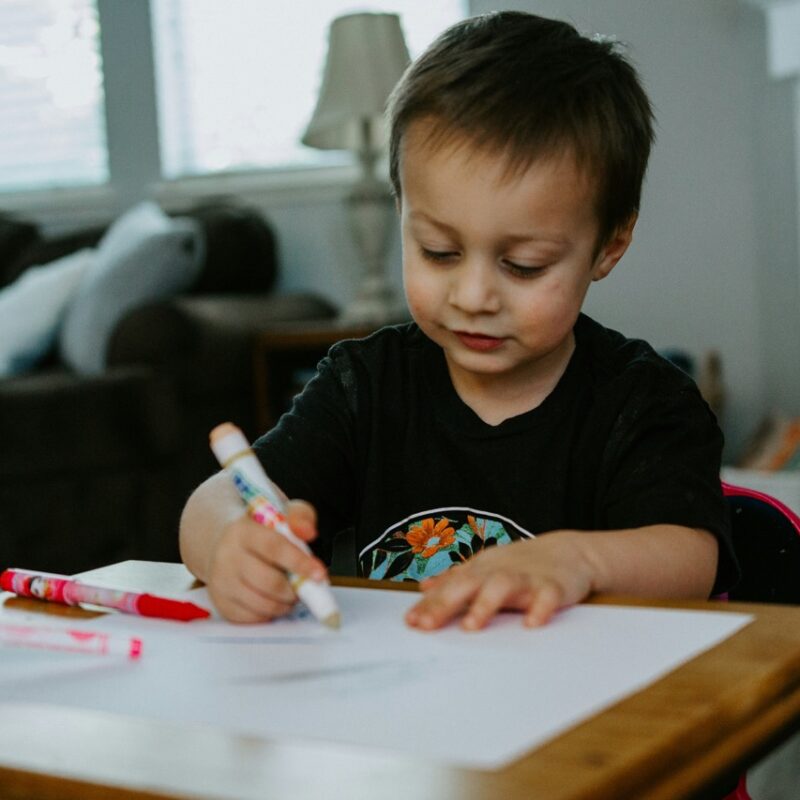 boy drawing with markers on a table in healthy environment
